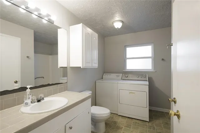 a bathroom with a granite countertop toilet a sink a mirror and a window