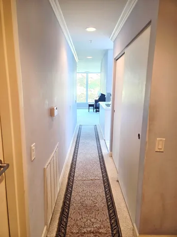 a view of a hallway with wooden floor and a bathroom