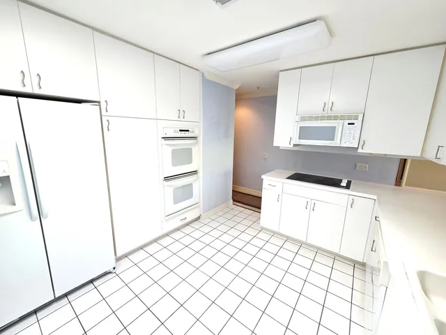 a kitchen with a refrigerator and white cabinets
