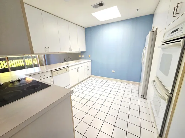 a large white kitchen with a sink and a large window