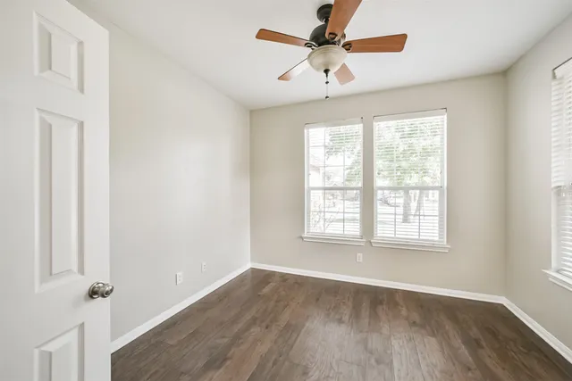 a view of an empty room with a window and wooden floor