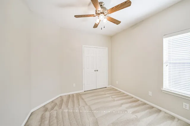 an empty room with a window and a fan