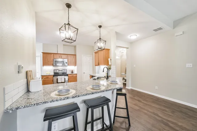 a dining room with granite countertop wooden floor and chandelier