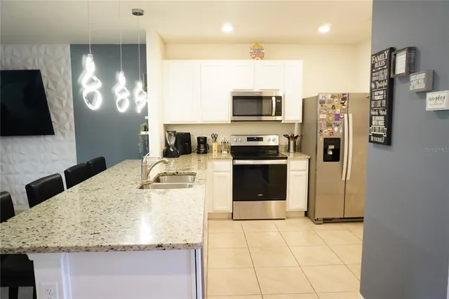 a kitchen with stainless steel appliances granite countertop a sink refrigerator and microwave