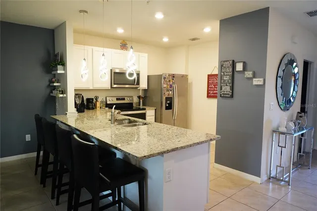 a kitchen with stainless steel appliances granite countertop a table chairs and a refrigerator