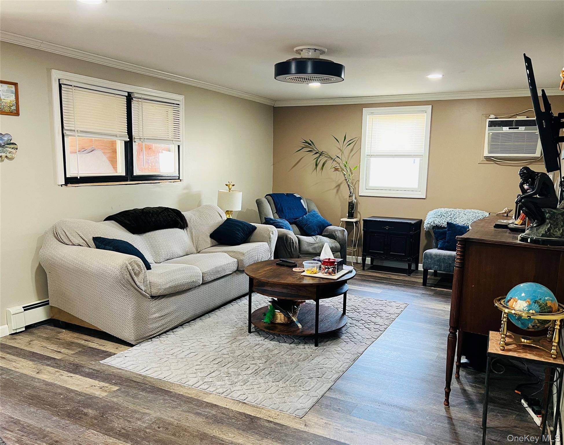 38 Riviera Drive Selden, NY 11784 - Photo 3 of 12 Family Room featuring wood-like floors, crown molding, baseboard heating, an AC wall unit, and recessed lighting