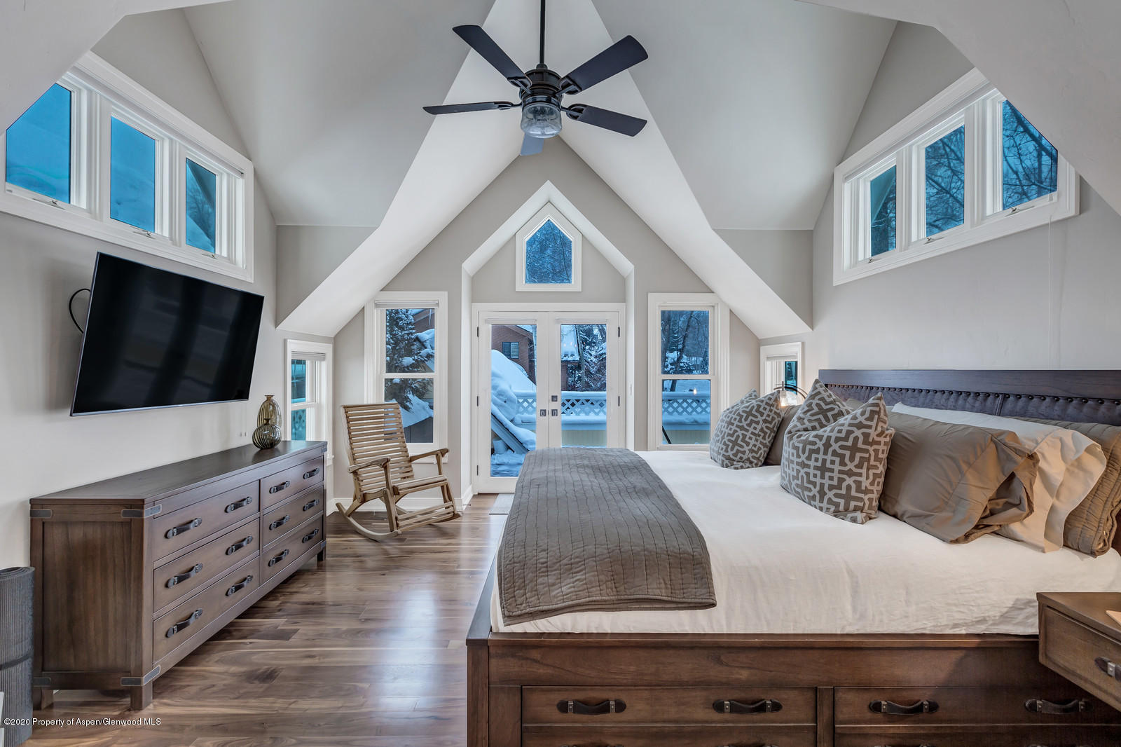 a bedroom with a large bed a flat tv screen and dresser