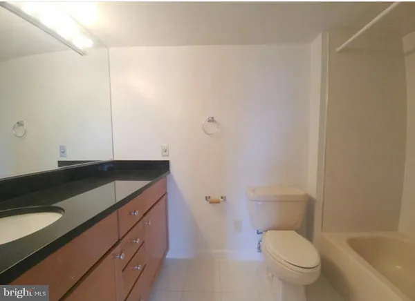 a bathroom with a granite countertop sink a toilet and bathtub