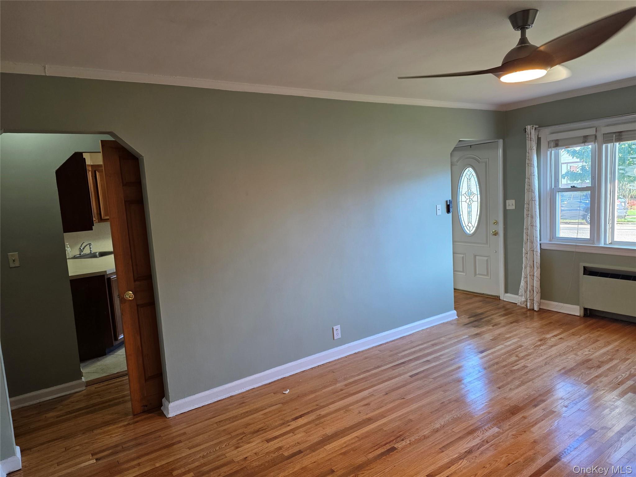 220 Raff Avenue Mineola, NY 11501 - Photo 7 of 22 Entrance foyer featuring wood finished floors, ornamental molding, a ceiling fan, arched walkways, and radiator