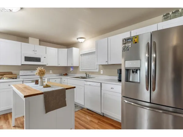 a kitchen with stainless steel appliances granite countertop a refrigerator sink and white cabinets