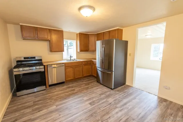 a kitchen with stainless steel appliances a refrigerator and wooden floor