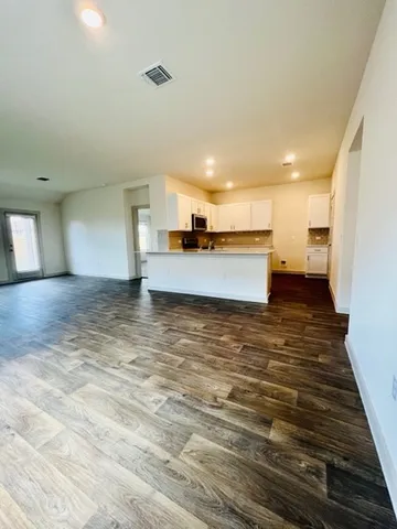 a view of a kitchen with kitchen island a sink wooden floor and a counter top space