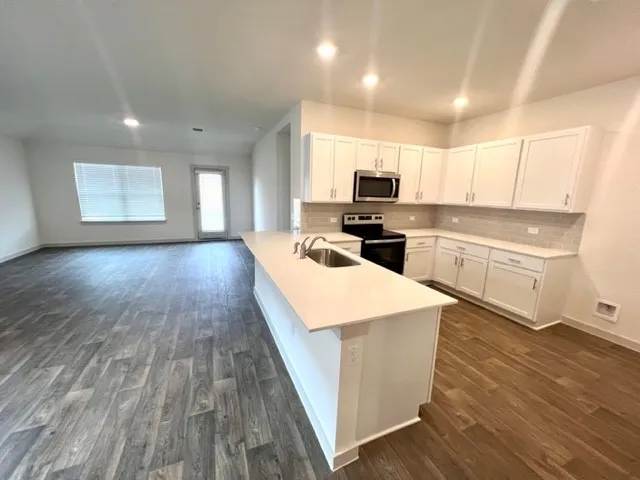 a large kitchen with stainless steel appliances a large counter top a stove a sink and a refrigerator