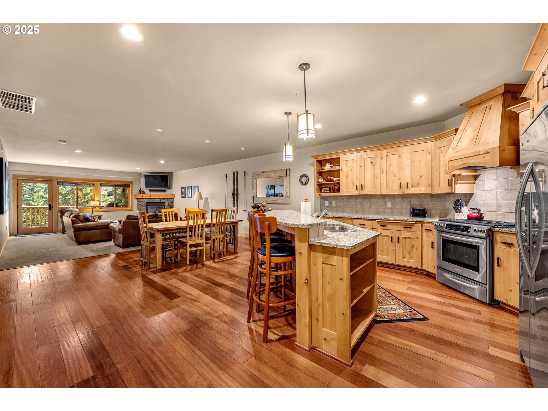 31254 East Collins Lake Road, Unit 22 Government Camp, OR 97028 - Photo 12 of 44 a open kitchen with stainless steel appliances granite countertop a stove top oven a sink a dining table and chairs with wooden floor