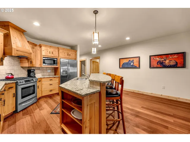 a kitchen with stainless steel appliances granite countertop a kitchen island hardwood floor sink stove dining table and chairs