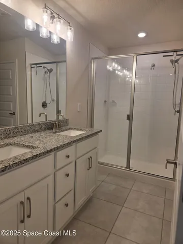 a bathroom with a granite countertop sink a mirror and a shower