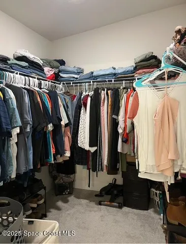 a view of walk in closet with clothes and shoes