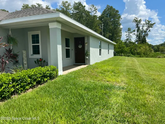 a view of a house with brick walls and a yard with plants