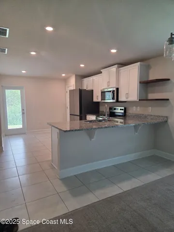 a view of kitchen with kitchen island stainless steel appliances refrigerator sink and cabinets