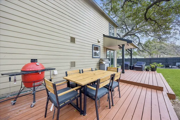 a view of a backyard with table and chairs potted plants and large tree