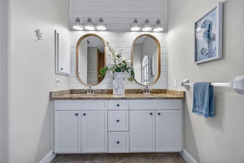 a bathroom with a granite countertop double vanity sink and a mirror