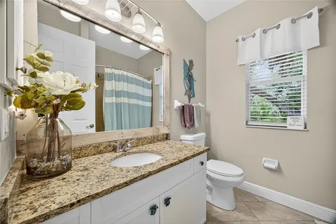 a bathroom with a granite countertop sink a toilet and a mirror