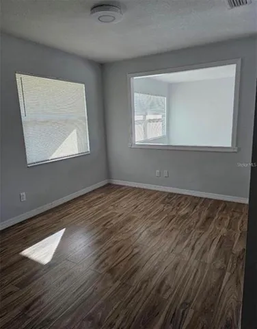 a view of an empty room with wooden floor and a window