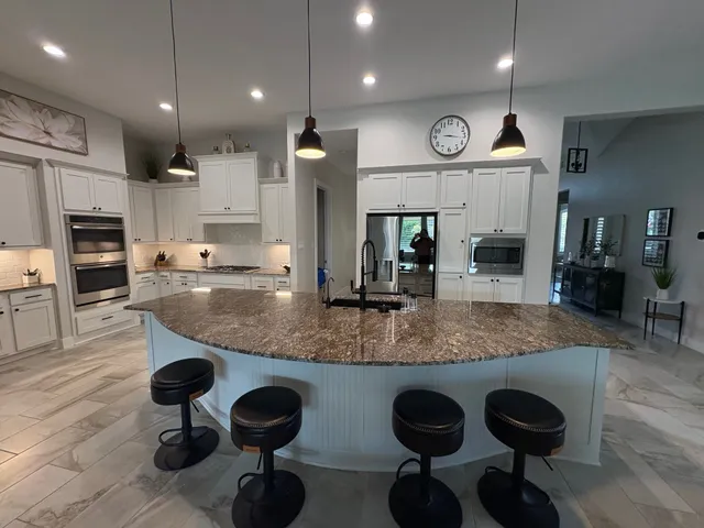 a kitchen with stainless steel appliances granite countertop a sink a stove and a wooden cabinets