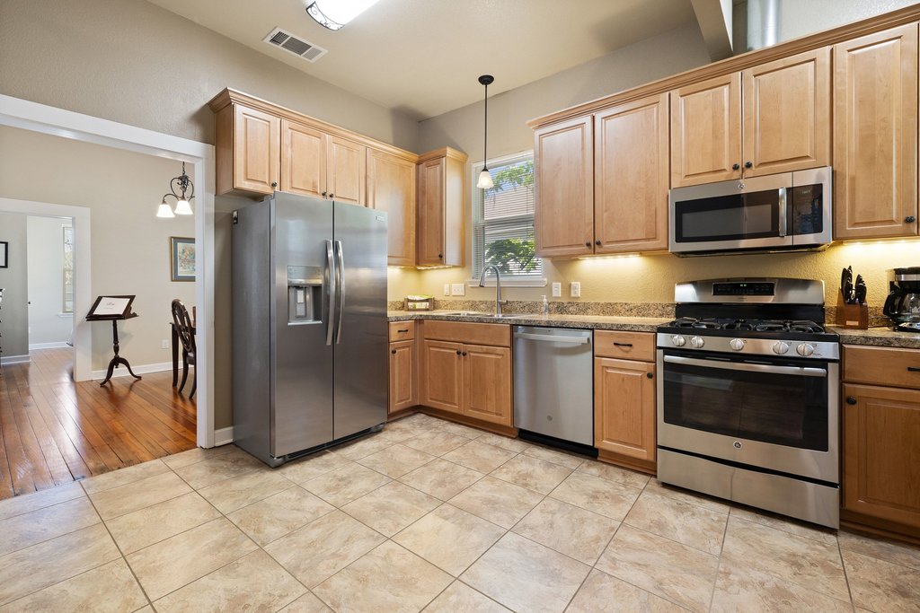312 West 3rd Street Taylor, TX 76574 - Photo 24 of 33 a kitchen with stainless steel appliances granite countertop a stove a sink and a refrigerator with cabinets