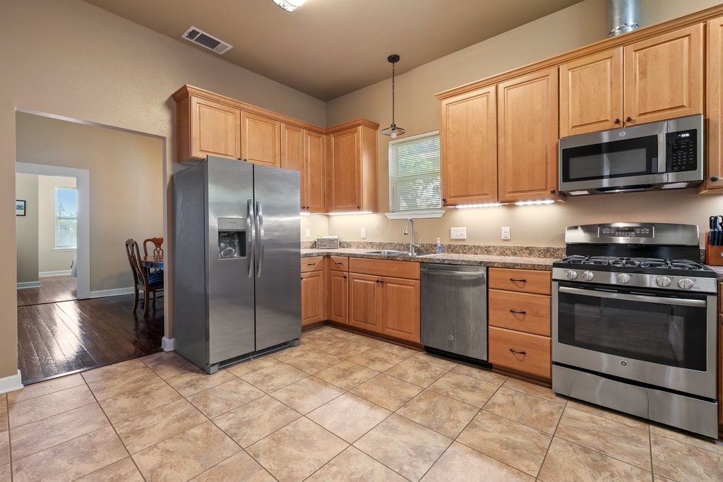 312 West 3rd Street Taylor, TX 76574 - Photo 9 of 33 a kitchen with stainless steel appliances granite countertop a stove a sink dishwasher a refrigerator and a microwave