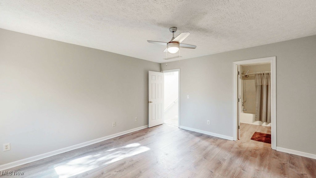 1426 Loop Road, Unit 1426 Kent, OH 44240 - Photo 15 of 40 View from the primary bedroom featuring a textured ceiling, light wood-type flooring, ceiling fan, and ensuite bath.