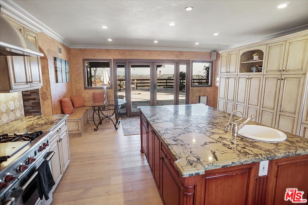 2270 Stradella Road Los Angeles, CA 90077 - Photo 8 of 29 a dining hall with stainless steel appliances granite countertop a stove top oven a dining table and chairs with wooden floor