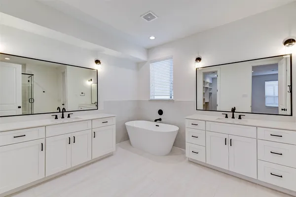a spacious bathroom with a double vanity sink mirror and bathtub