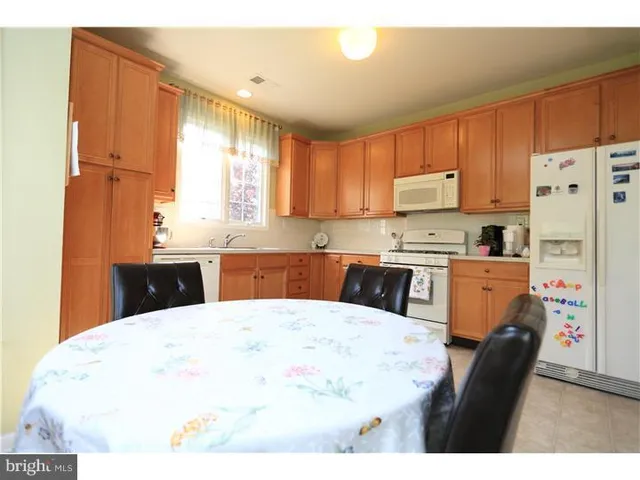 a kitchen with a refrigerator a stove a sink and white cabinets with wooden floor