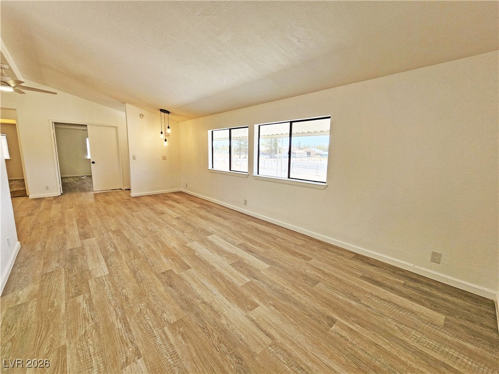1860 West Wilson Road Pahrump, NV 89048 - Photo 3 of 16 Unfurnished room with vaulted ceiling, light wood-style floors, a textured ceiling, and a ceiling fan