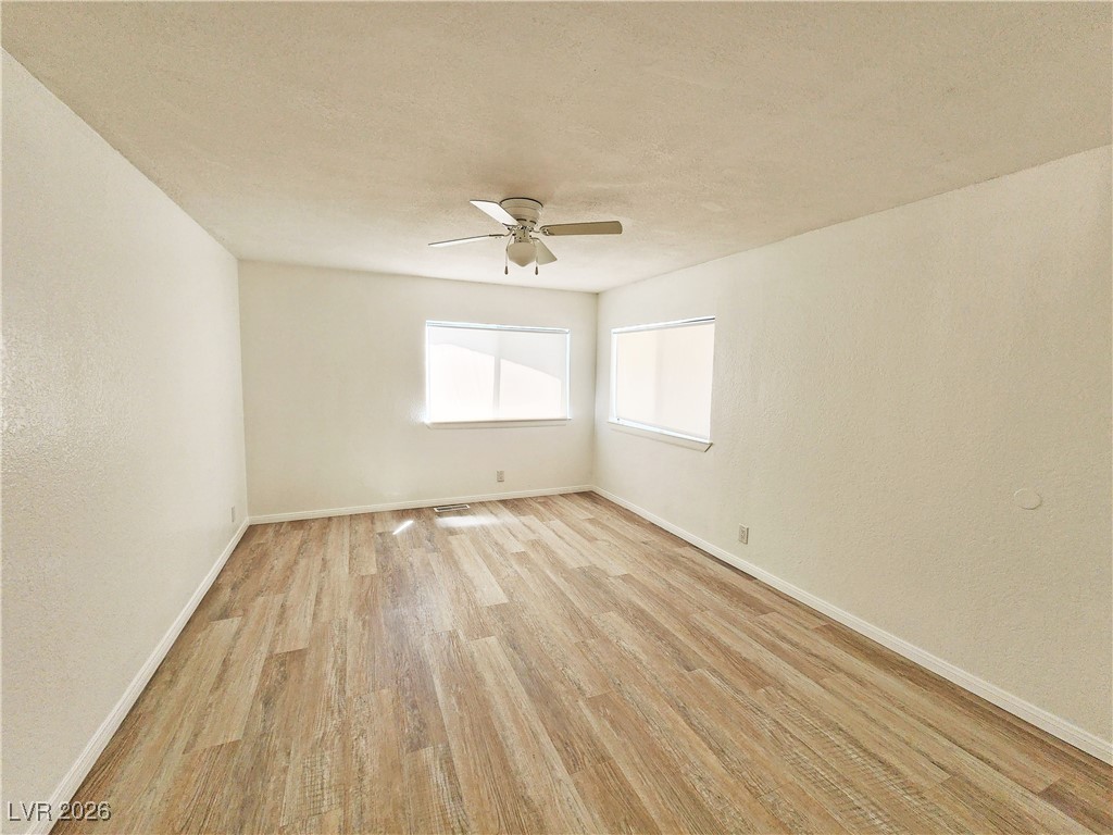 1860 West Wilson Road Pahrump, NV 89048 - Photo 6 of 16 Unfurnished room featuring light wood finished floors, a textured wall, a textured ceiling, and ceiling fan