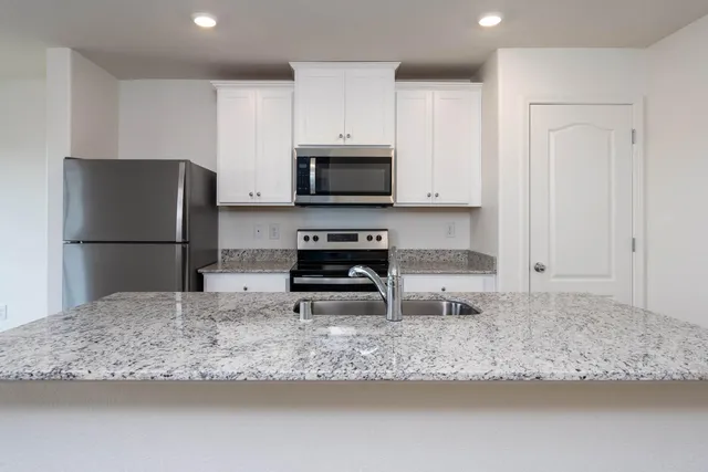 a kitchen with granite countertop a refrigerator and a stove top oven