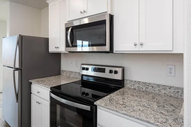 a kitchen with stainless steel appliances granite countertop a stove microwave and refrigerator