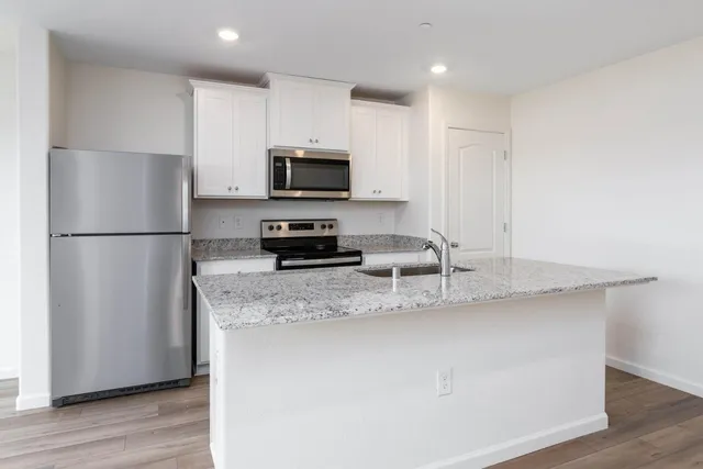 a kitchen with stainless steel appliances granite countertop a refrigerator a stove a sink a microwave a counter space and cabinets