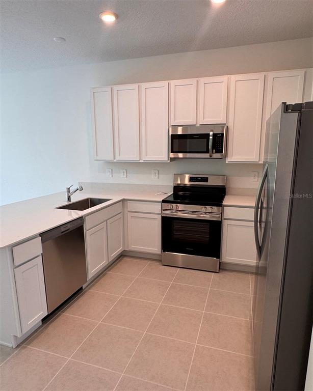 2769 Skyline Loop Kissimmee, FL 34758 - Photo 2 of 17 a kitchen with a sink a stove a microwave and cabinets