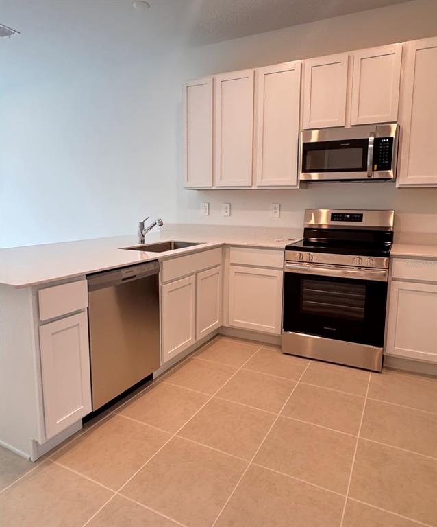2769 Skyline Loop Kissimmee, FL 34758 - Photo 5 of 17 a kitchen with stainless steel appliances granite countertop a sink dishwasher stove top oven and microwave