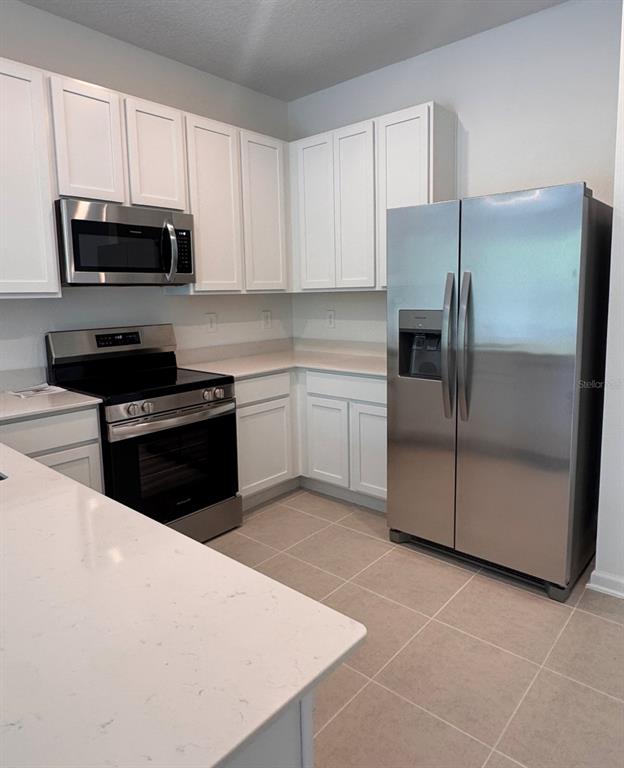 2769 Skyline Loop Kissimmee, FL 34758 - Photo 7 of 17 a kitchen with stainless steel appliances granite countertop a stove a microwave and a refrigerator