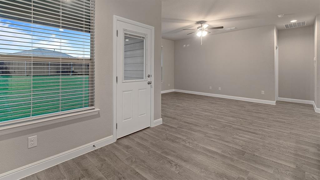 219 Windmill Drive Rhome, TX 76078 - Photo 5 of 29 an empty room with wooden floor and a ceiling fan