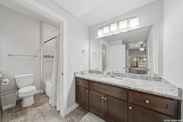 a spacious bathroom with a granite countertop sink a toilet and a mirror