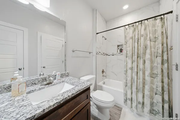 a bathroom with a granite countertop sink toilet and shower