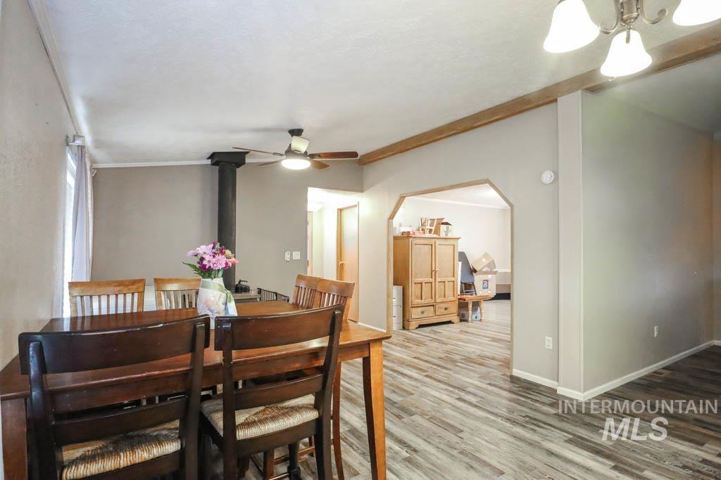 815 Eaton Road Weiser, ID 83672 - Photo 11 of 50 Dining space with wood finished floors, a wood stove, crown molding, and ceiling fan