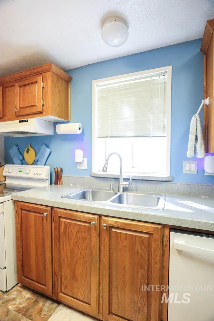 815 Eaton Road Weiser, ID 83672 - Photo 16 of 50 Kitchen with brown cabinets, white appliances, light countertops, and under cabinet range hood
