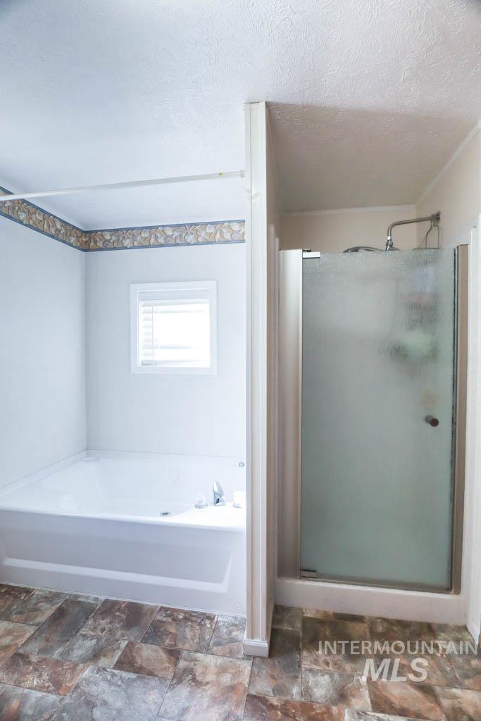 815 Eaton Road Weiser, ID 83672 - Photo 21 of 50 Bathroom featuring a bath, a shower stall, a textured ceiling, and dark stone finish flooring