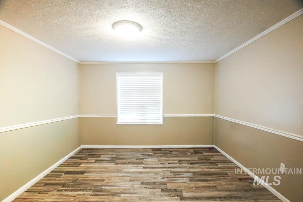 815 Eaton Road Weiser, ID 83672 - Photo 25 of 50 Unfurnished room with a textured ceiling, wood finished floors, and crown molding