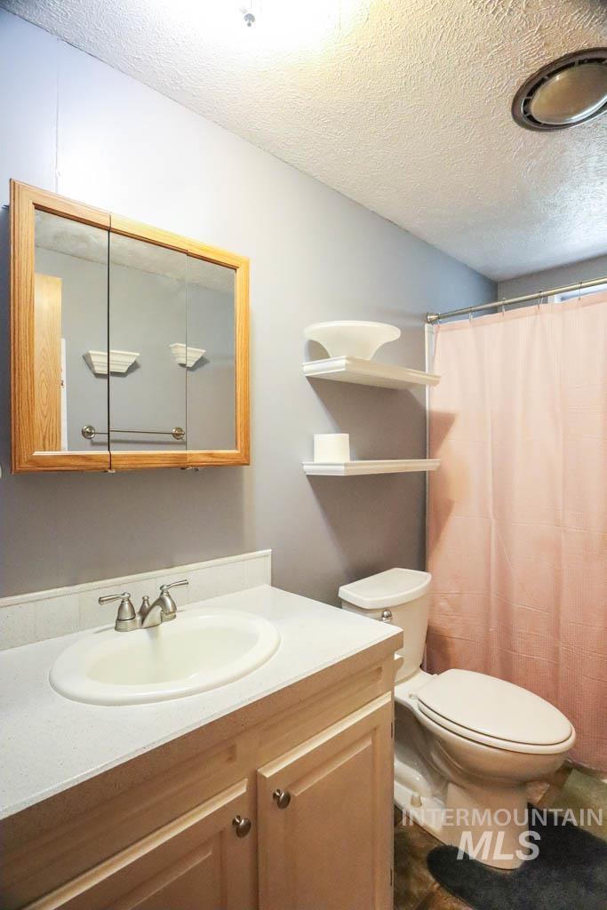 815 Eaton Road Weiser, ID 83672 - Photo 27 of 50 Bathroom featuring a textured ceiling, vanity, and a shower with shower curtain